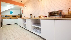 A modern kitchen with white cabinets, a brick wall backsplash, hanging pendant lights, and a built-in oven. - Best Guest Porto Hostel (Porto)