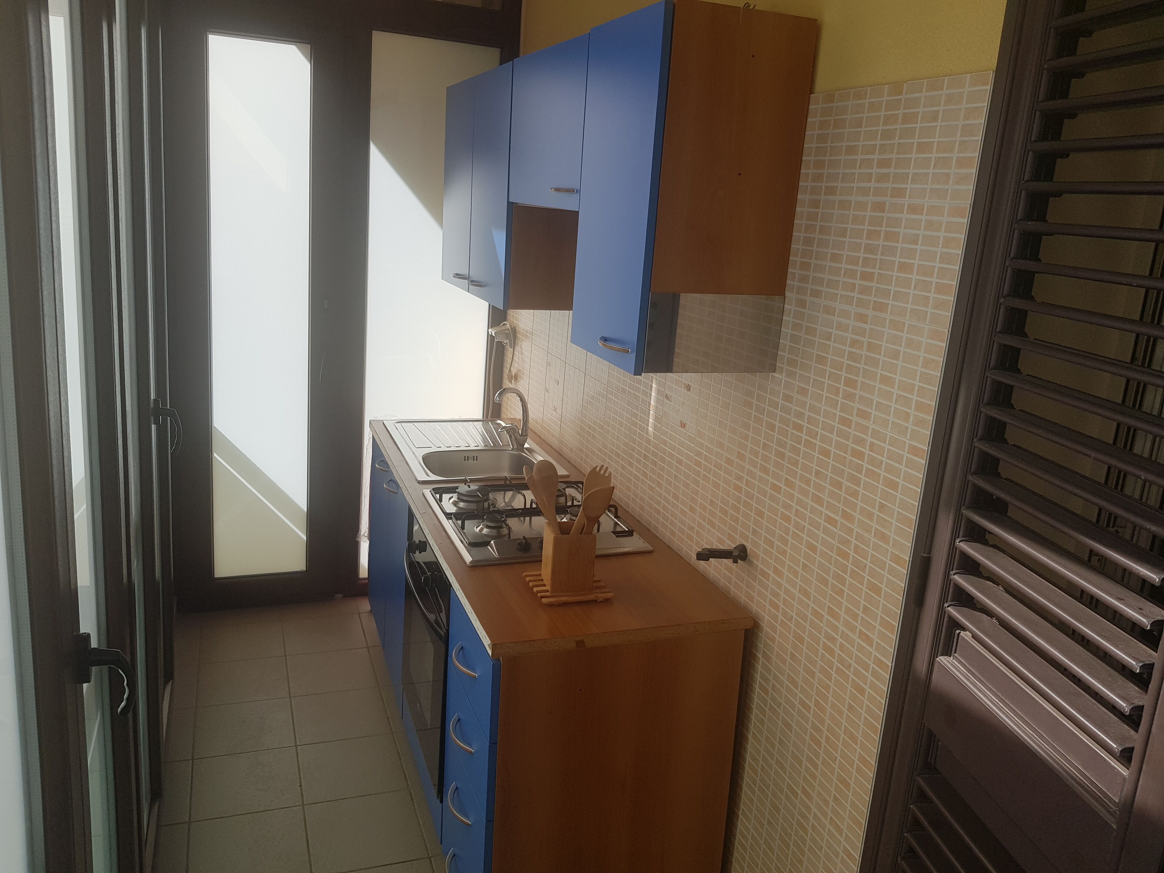 A kitchen with blue cabinets, a wooden countertop, a gas stove, and a window.