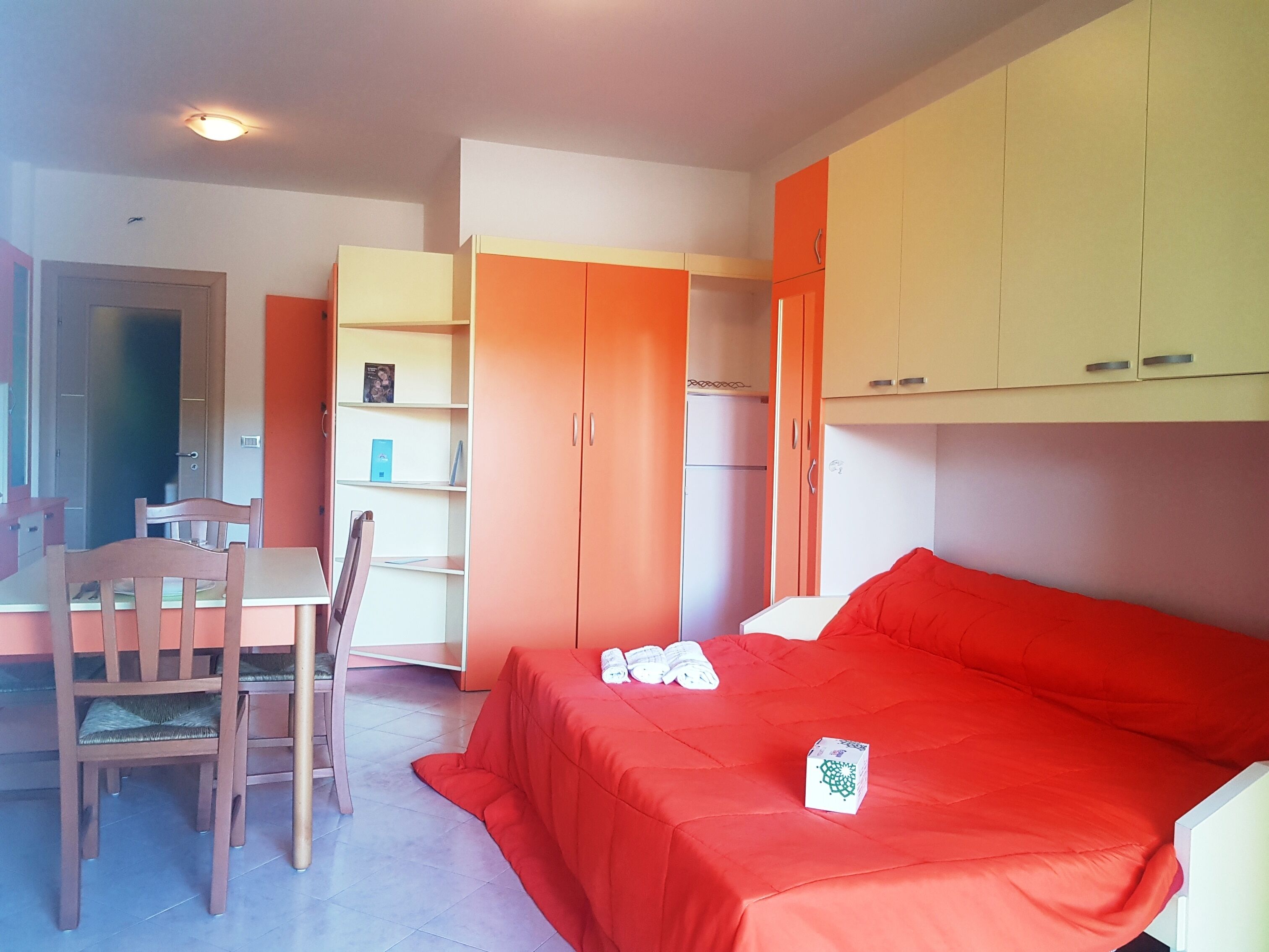 Ein Zimmer mit Bett, Schreibtisch, Stuhl und Kleiderschrank.