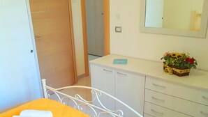 Una habitación de hotel con una cama, un aparador, un espejo y un pequeño arreglo floral sobre el aparador.