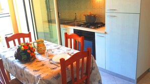 Una cocina con una mesa de comedor para dos personas, estufa y refrigerador.