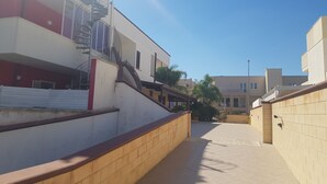Un estrecho callejón con un edificio a la izquierda que tiene una escalera y un balcón.