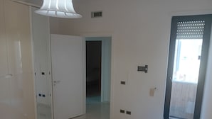 Un dormitorio con cama, armario, puerta y ventana.