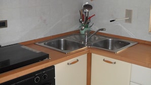 Una cocina con dos fregaderos, estufa y alacenas.