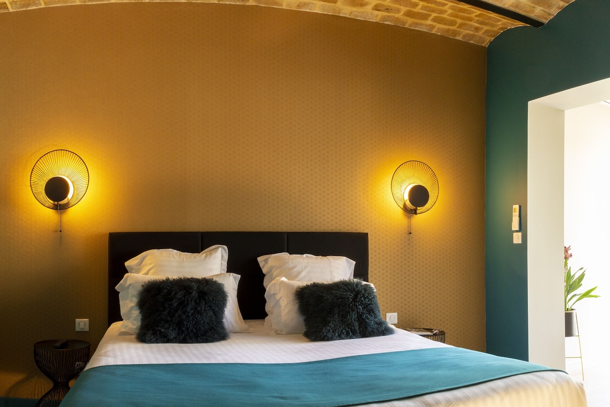 Une chambre d’hôtel avec un lit, deux lampes fixées au mur et une vue sur l’extérieur.