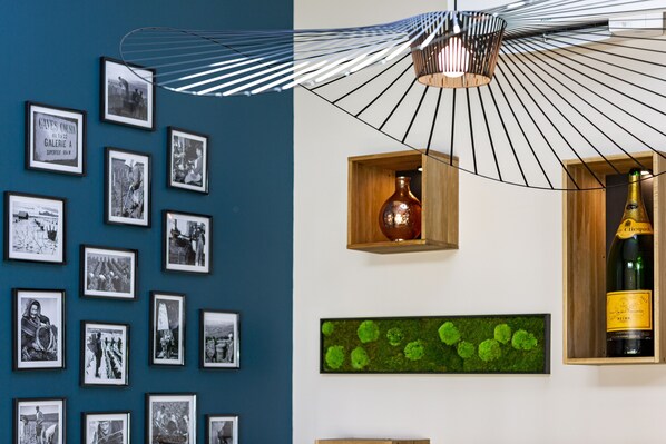 A wall with framed photographs and a wooden wine bottle display.