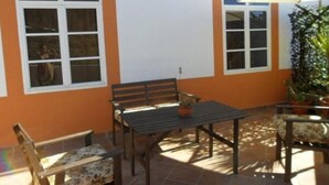 An outdoor patio with a table and chairs, a bench, and a potted plant. - Casa Rural las Cáscaras (Tejeda)