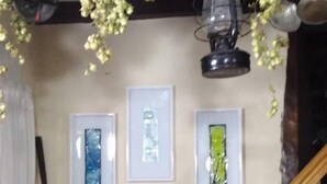 Un escalier avec une rampe en bois, un mur orné de trois œuvres d’art encadrées et une lanterne suspendue.