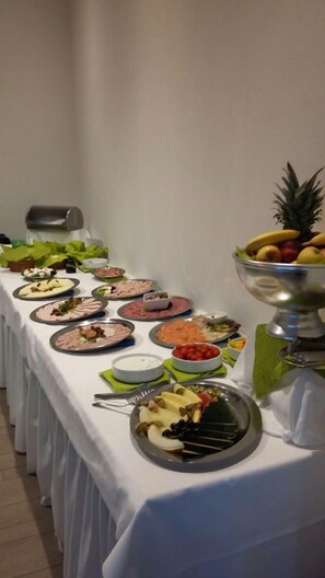 A buffet table with various food items and a fruit bowl.