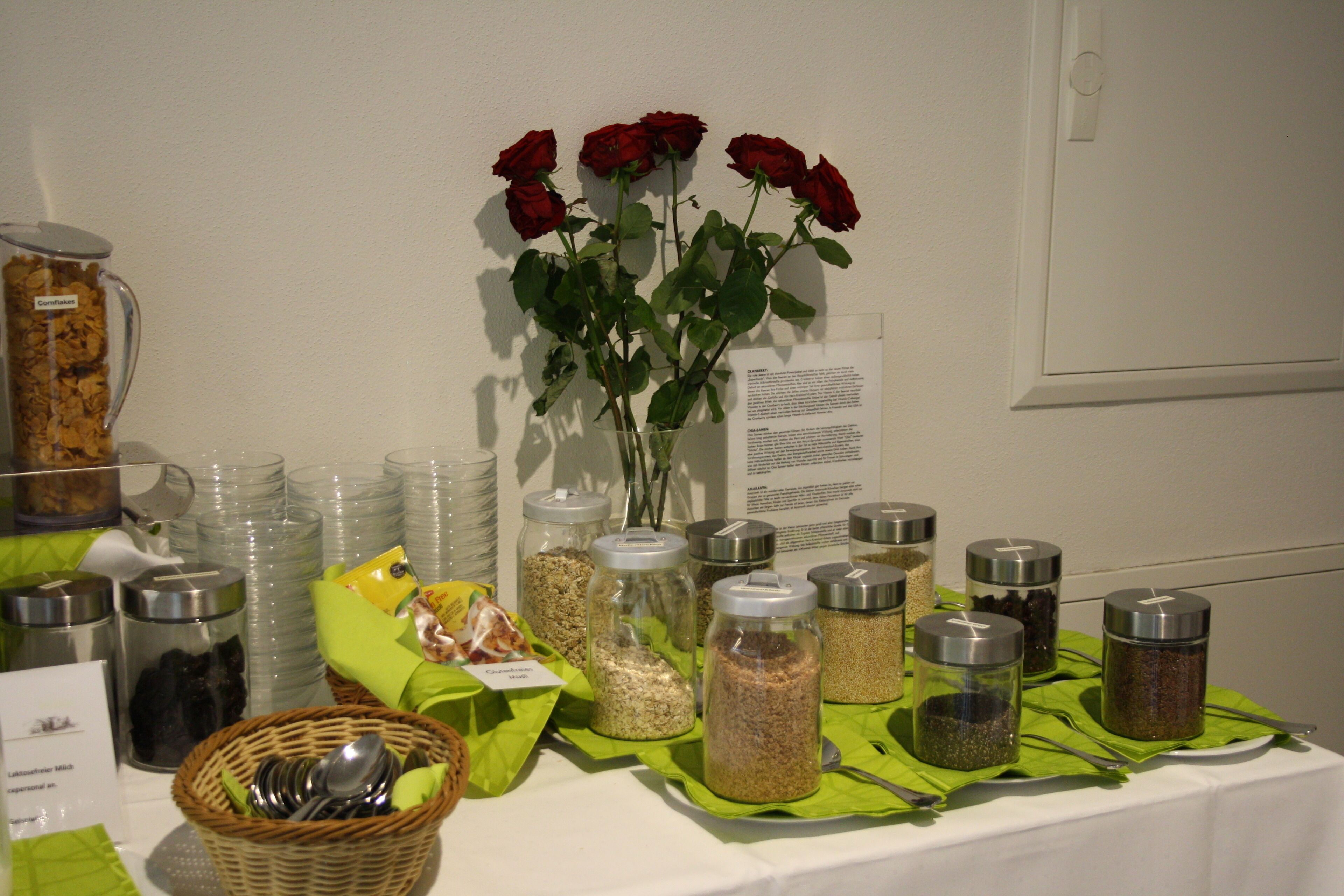 A table with various food items and a vase of red roses.