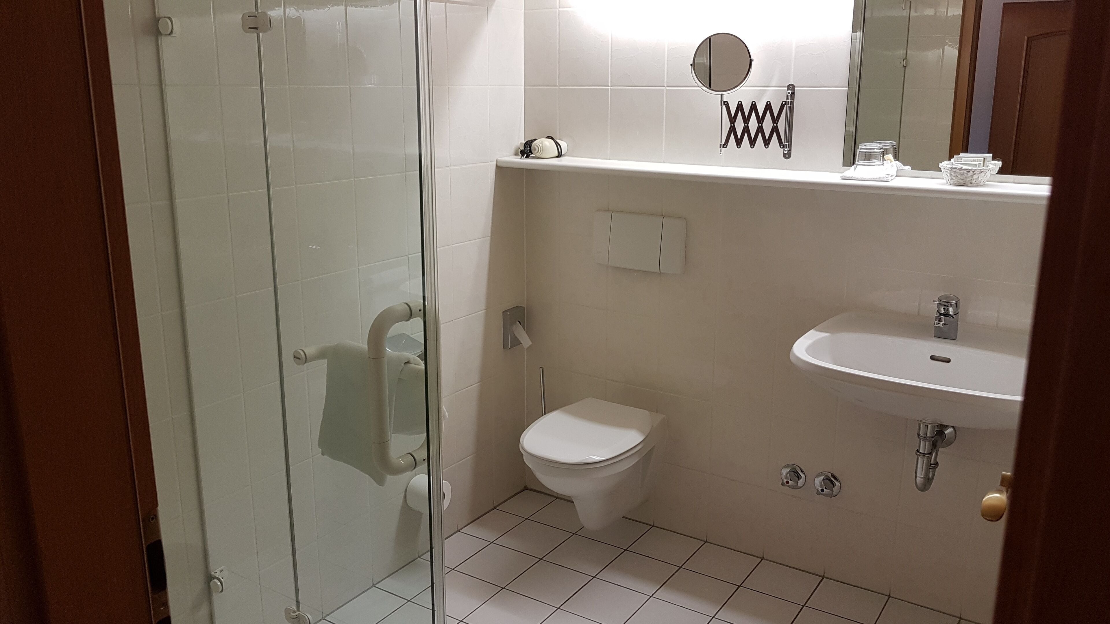 Un baño moderno con cabina de ducha de vidrio, inodoro, lavabo y espejo.