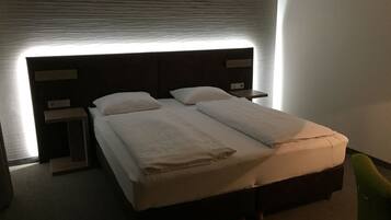 A hotel room with a bed, nightstands, and a green chair.