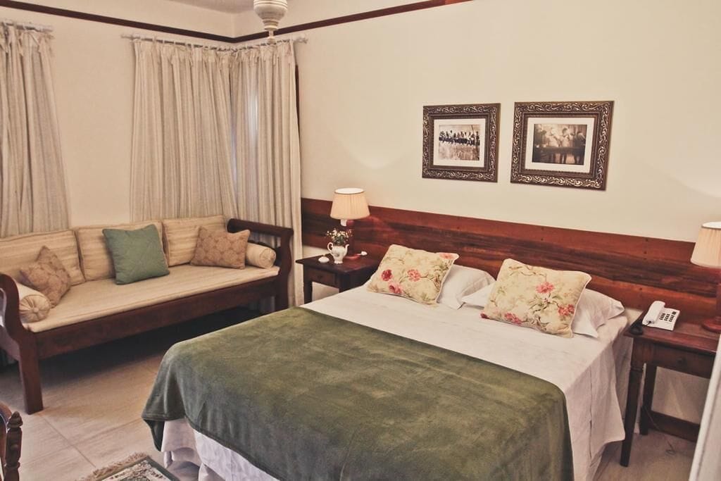 Une chambre à coucher comprenant un lit, un canapé, une table de chevet et deux tableaux encadrés accrochés au mur.