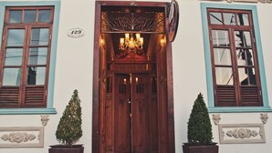 Una entrada de madera con un candelabro, dos árboles en macetas y un letrero con el número 129.