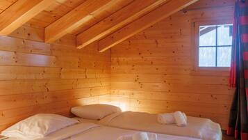 Une chambre confortable de style cabane, avec deux lits, des murs en bois et un plafond en pente.