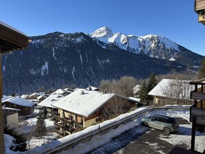 Une vue sur la montagne, avec des bâtiments enneigés et une voiture garée.