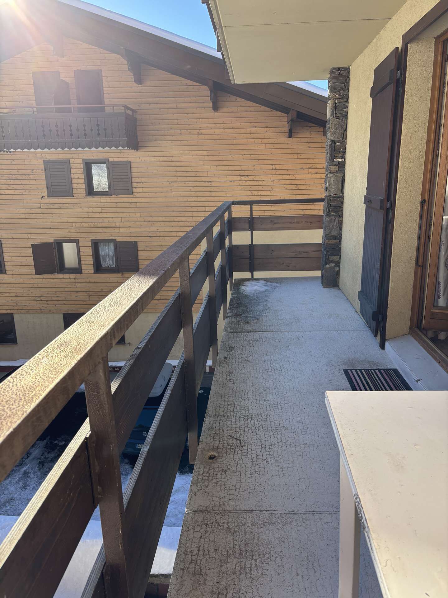 En byggnad av trä med en balkong, en stenmur och en dörr.