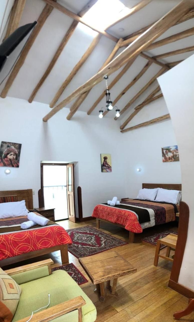 Een kamer met twee bedden, houten balken in het zicht en een klein tafeltje.