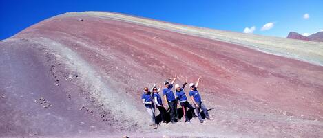 A group of people posing on a rocky slope with a clear blue sky.