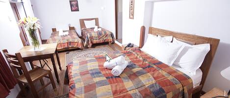 Habitación de hotel con dos camas, un escritorio de madera, una silla, una mesita pequeña y una mesita de noche.
