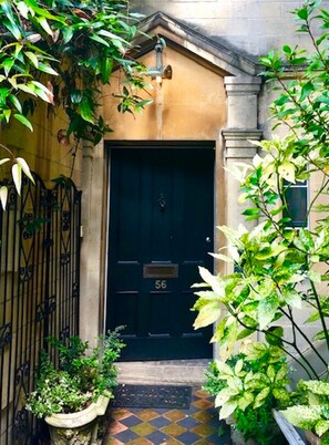 A black door with the number 56, a small step leading up to it, and a metal gate to the left. - Laura’s Townhouse Apartments Balloon Watchers Retreat   (Bath)