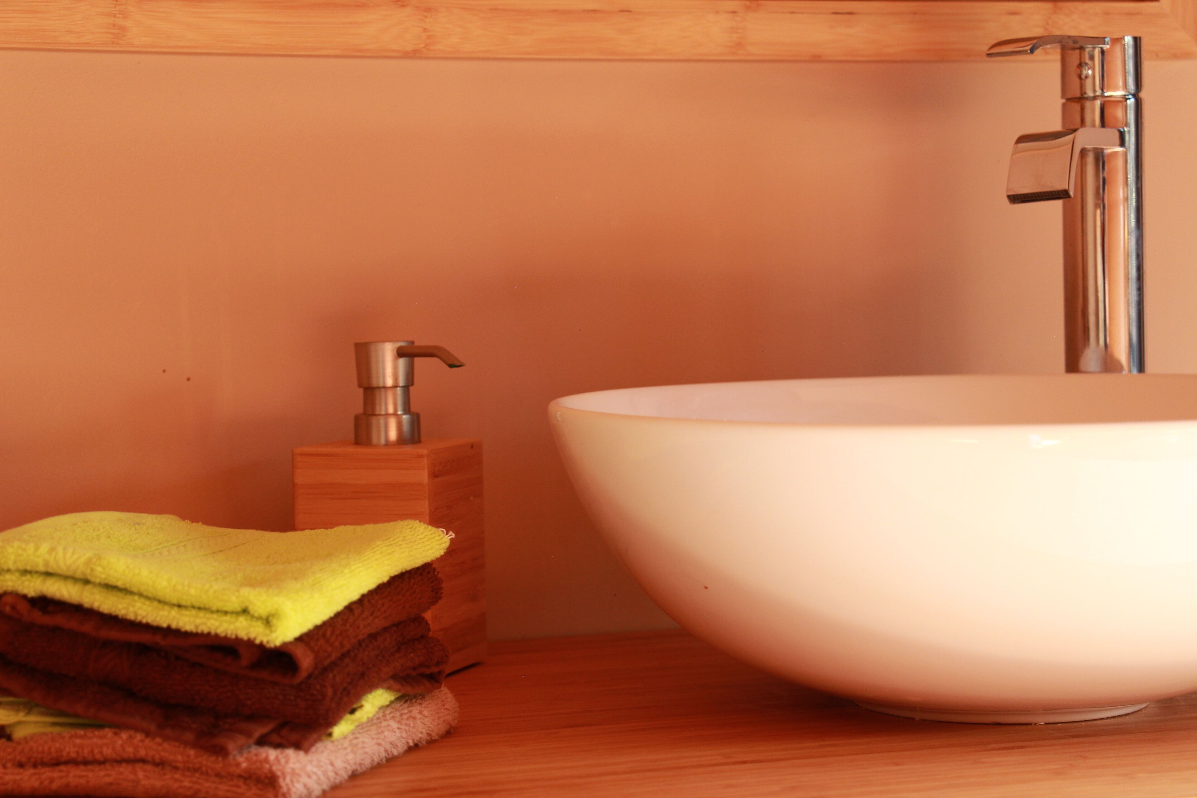 A bathroom with a white sink, wooden cabinet, and a stack of folded towels.