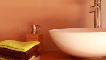 A bathroom with a white sink, wooden cabinet, and a stack of folded towels.