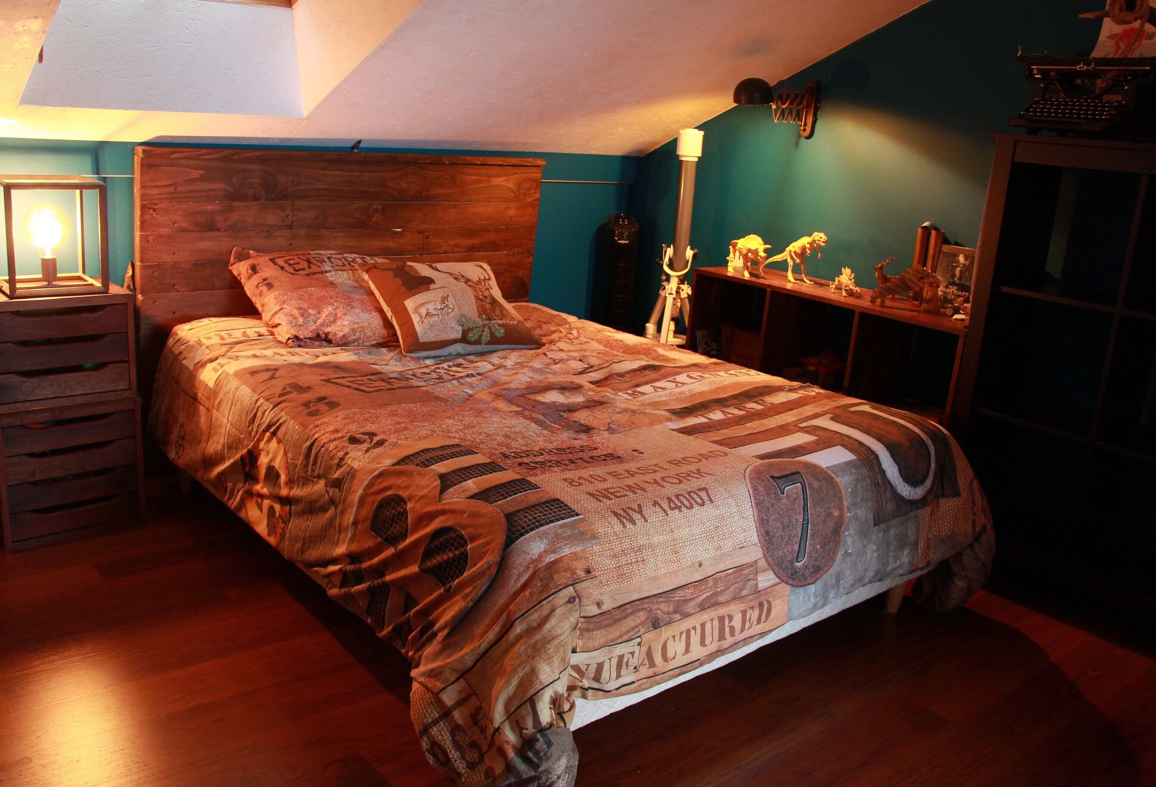 A bedroom with a wooden headboard, a bed with a patterned bedspread, a nightstand with a lamp, and a shelf with decorative items.