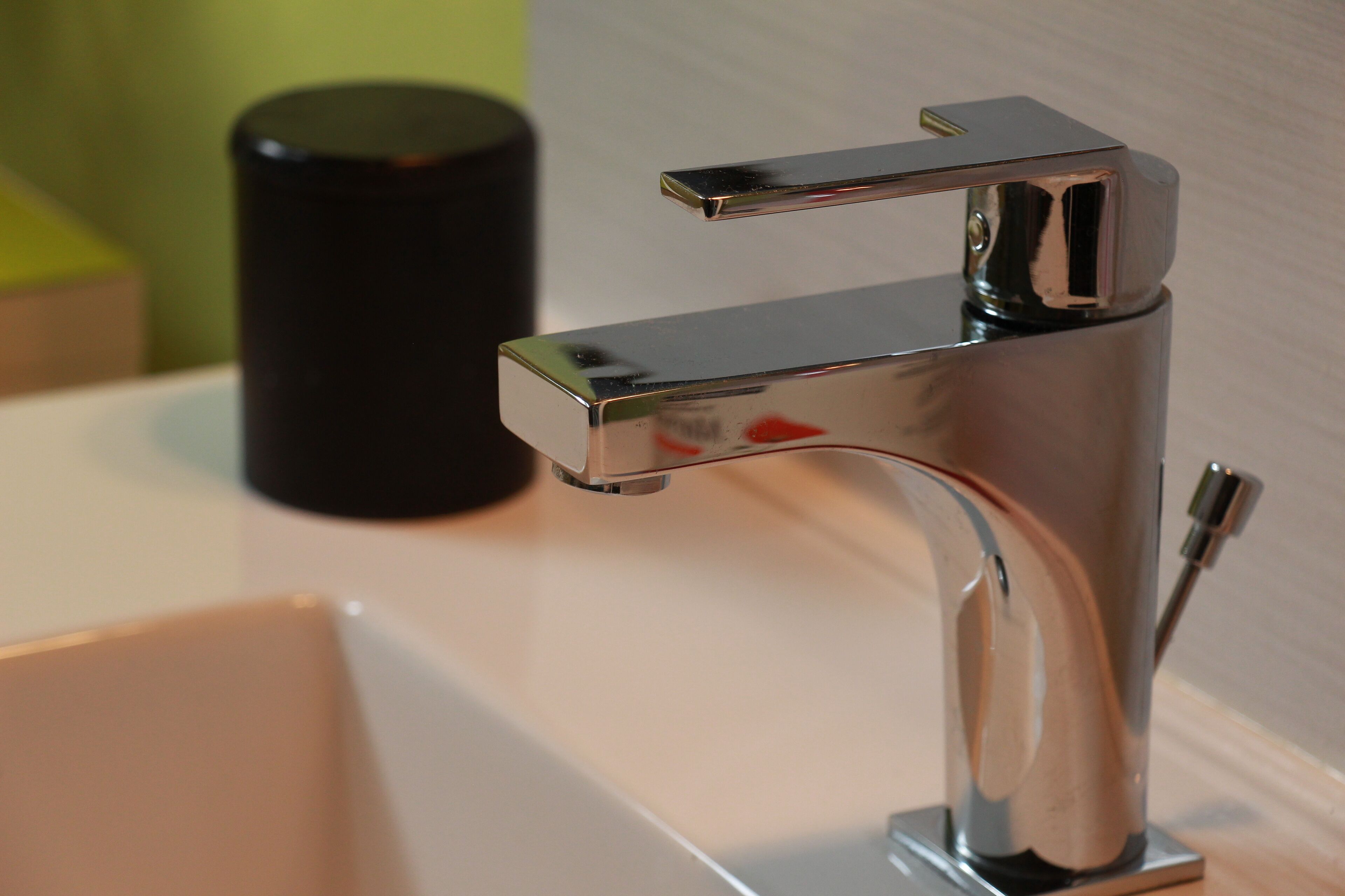 A chrome faucet with a single handle and a side lever, mounted on a white countertop.