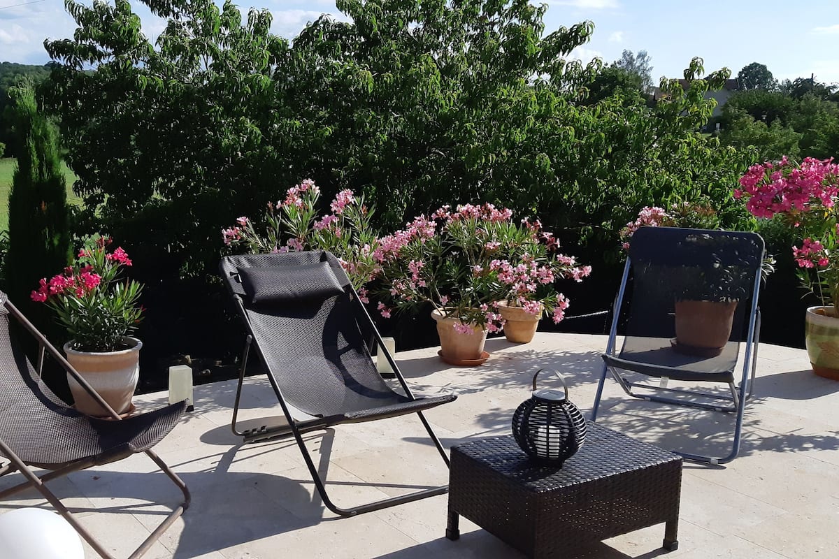 A patio with two lounge chairs, a small table, and potted plants.