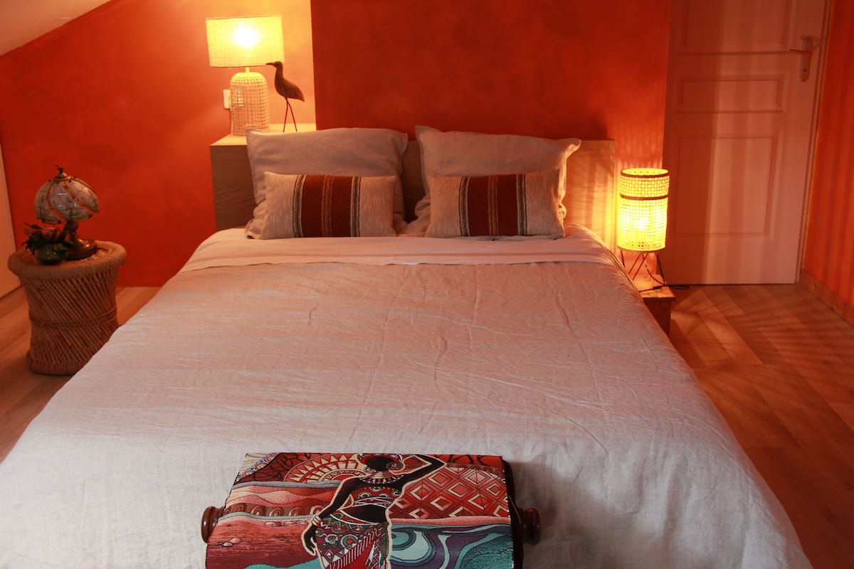 A bedroom with a large bed, two bedside lamps, and a globe on a side table.