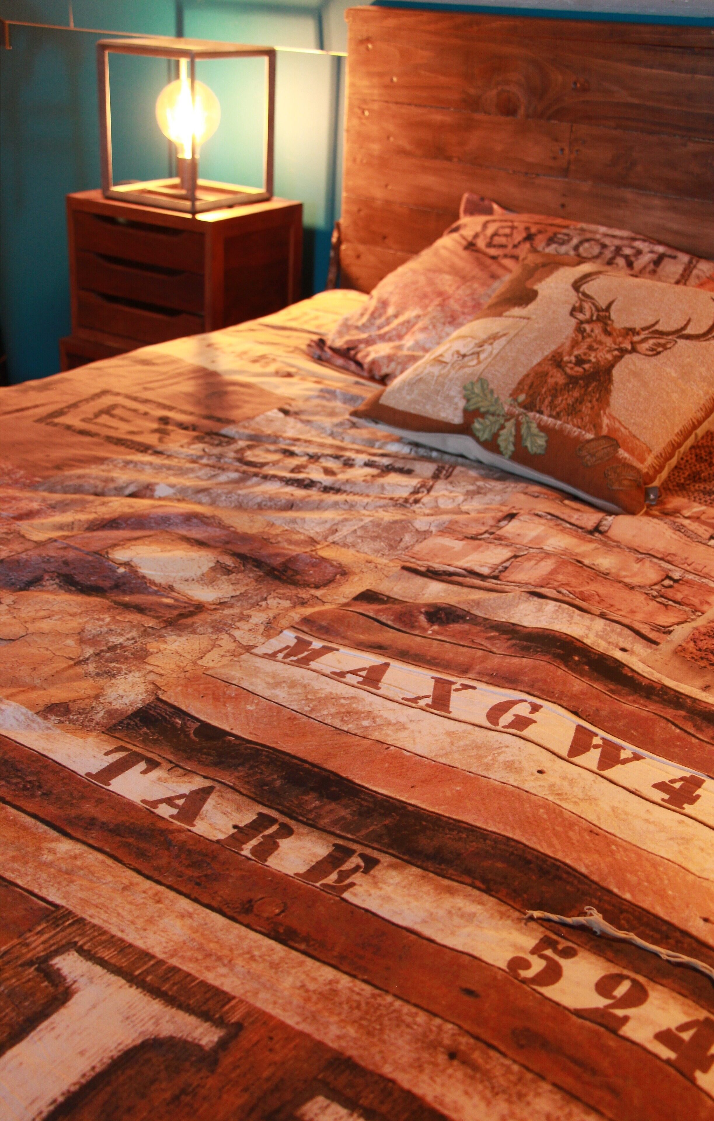 Una cama con una colcha estampada y una mesita de noche con una lámpara.