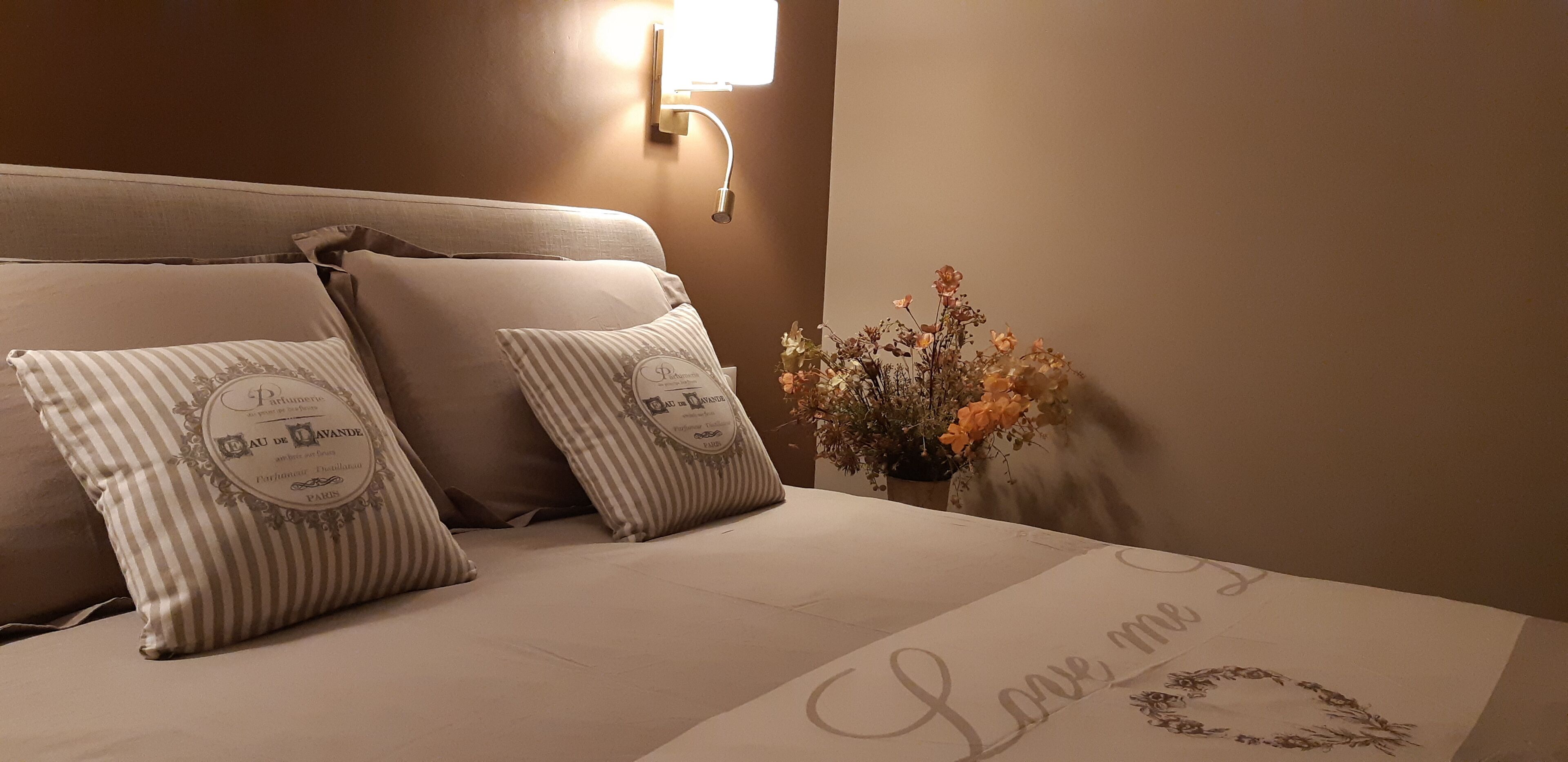 Una cama bien hecha con almohadas y un aplique decorativo en la pared.