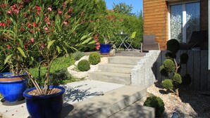 Ein Holzhaus mit Terrasse, Blumentöpfen und Gartenmöbeln.