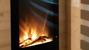 Ein Kamin mit Feuer, eine hängende Pflanze und eine Wandleuchte.