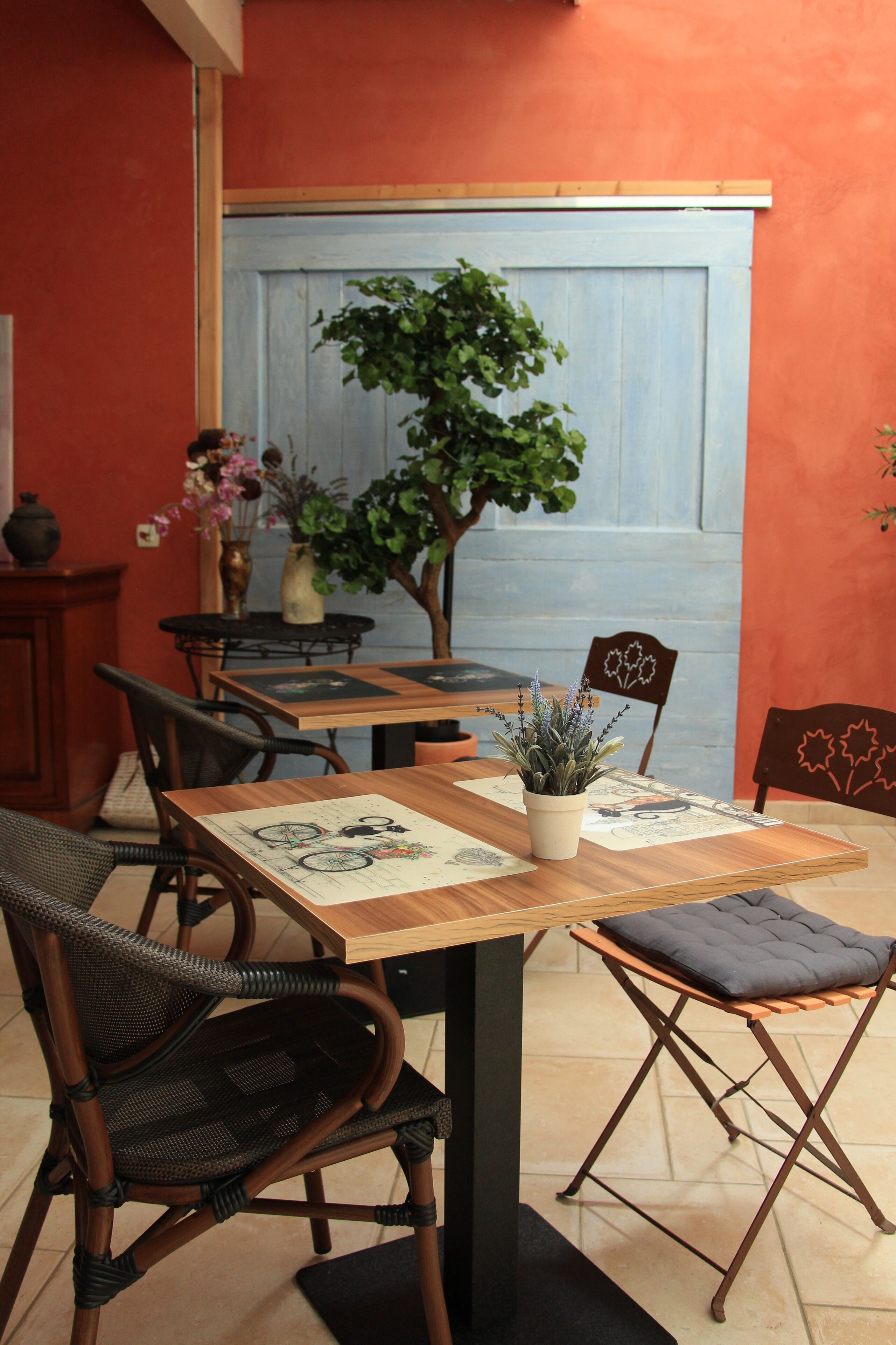 Un comedor con mesa de madera, sillas de mimbre y una planta en maceta.