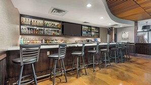 A bar area with a wooden ceiling, multiple shelves of liquor bottles, and bar stools. - Best Western Plus Lakeview Hotel (Madison)