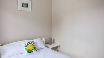 A bedroom with a bed, a bedside table, a lamp, and a framed picture on the wall.