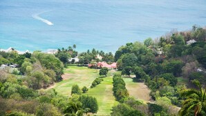 A golf course with a view of the ocean and surrounding greenery.