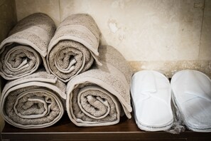 A stack of rolled towels and a pair of white shoes on a wooden surface.