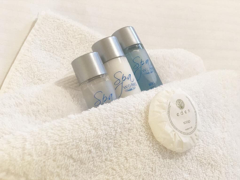 Tres botellas de productos de spa y una pastilla de jabón sobre una toalla blanca.