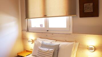 Ein Schlafzimmer mit einem Holz-Kopfteil, einem Fenster mit Jalousien, zwei Nachttischlampen und einem Nachttisch.