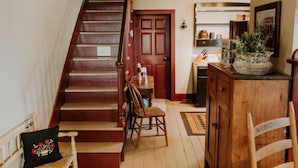 Un escalier menant à un palier où se trouvent une chaise en bois et un coussin décoratif.