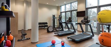 A gym with treadmills, exercise balls, and weights.