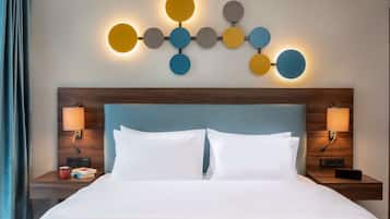 A hotel room with a neatly made bed, two bedside tables with lamps, and a wall-mounted light fixture.