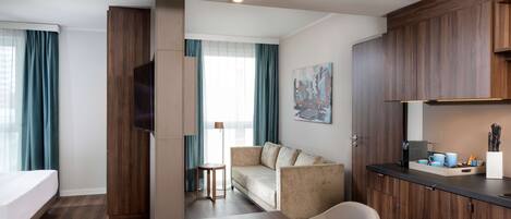 Una habitación de hotel con cama, sofá, mesa de comedor y kitchenette.