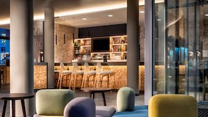 Un espace bar moderne, doté de sièges, d’un téléviseur et d’un assortiment de bouteilles.