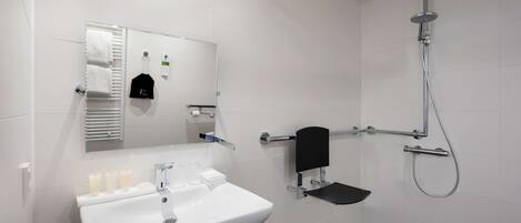 Un baño moderno con lavamanos, espejo y ducha blancos.