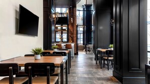 A modern restaurant interior with a long counter, multiple seating areas, and a large TV mounted on the wall. - Hyatt House Nashville Downtown/Convention Center (Nashville)