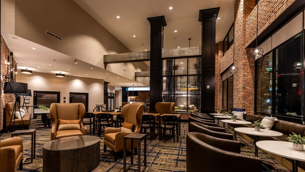A spacious lobby with leather seating, a patterned carpet, and a brick wall. - Hyatt House Nashville Downtown/Convention Center (Nashville)